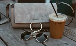 Zamszowa torebka Chloe, okulary i kawa na drewnianym stole. Dowiedz się, jak wyczyścić zamszową torebkę, by wyglądała jak nowa.