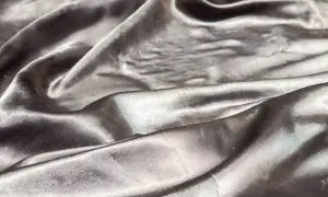 Gładki, połyskliwy materiał modakryl układa się w miękkie fale, odbijając światło.