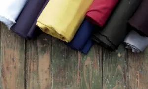 Rolki materiałów w różnych kolorach: białym, granatowym, żółtym, czerwonym, czarnym i szarym. To świetny materiał, czyli cotton, idealny do szycia.