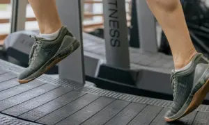 Dobre buty na bieżnię to klucz do komfortowego treningu. Na zdjęciu widać nogi w zielonych, sportowych butach na bieżni.