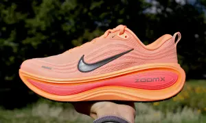 Pomarańczowy but do biegania Nike z czarnym logo i podeszwą ZoomX.