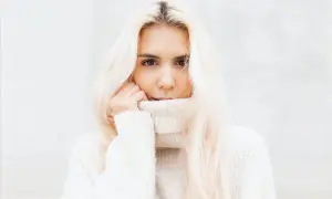 Blondynka w białym golfie, z włosami opadającymi na ramiona, wygląda jak uosobienie stylu vanilla girl.