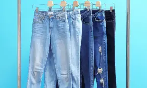 Różne modele jeansów damskich na wieszakach. Czy rozmiar 26 spodnie damskie to odpowiedni wybór?