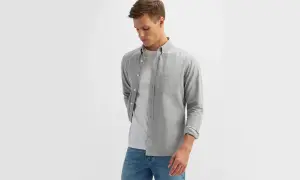 Młody mężczyzna w szarej koszuli i białej koszulce, prezentujący wygodny strój casual męski.
