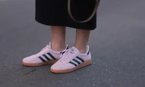 Różowe buty sportowe Adidas z granatowymi paskami i brązową podeszwą.