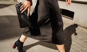 Eleganckie botki na słupku świetnie pasują do sukienki za kolano. Czarna, pikowana kopertówka dopełnia stylizację.