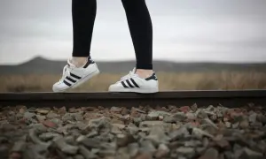 Białe trampki Adidas Superstar z czarnymi paskami i czarne legginsy – idealne buty do legginsów na spacer po torach kolejowych.