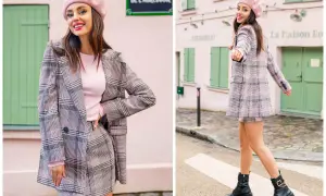 Kobieta w różowym beretce i kraciastym komplecie, który podkreśla jej styl etniczny. Uśmiecha się, pozując na tle paryskiej uliczki.