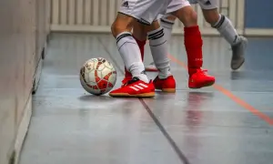 Piłka nożna na hali, gracze w czerwonych butach i białych strojach. Czy w turfach można grać na hali? Tak, to właśnie dzieje się na tym zdjęciu!