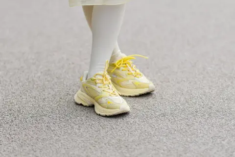 Żółte sneakersy na nogach w białych skarpetkach. Czy 36 rozmiar buta ile to cm?