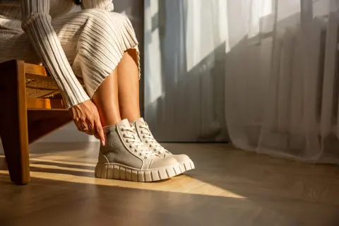 Damskie buty Palladium w beżowo-szarym kolorze na grubej podeszwie, noszone z dzianinową sukienką.