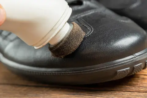 Domowe sposoby na rysy na butach: aplikator z pastą do butów usuwa drobne zarysowania z czarnego, skórzanego obuwia.