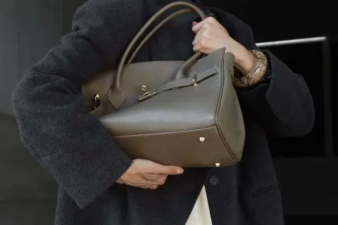 Elegancka, szara torebka na ramię z uchwytami i złotymi elementami. Klasyczne, jakie torebki są teraz modne, to te o prostych, ponadczasowych formach.