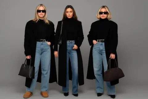 Trzy kobiety w czarnych płaszczach i jeansach prezentują jeansy eleganckie stylizacje.