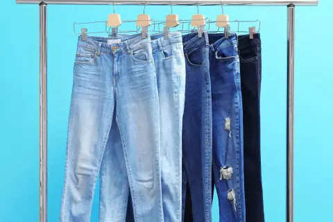 Różne modele jeansów damskich na wieszakach. Czy rozmiar 26 spodnie damskie to odpowiedni wybór?