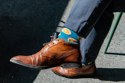 Niebieskie skarpetki w pomarańcze dodają charakteru do eleganckiego garnituru. Idealne pytanie: jakie skarpetki do garnituru?