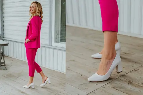 Elegancka kobieta w fuksjowym garniturze i białych czółenkach na słupku. Idealne buty do damskiego garnituru, które dodają klasy.