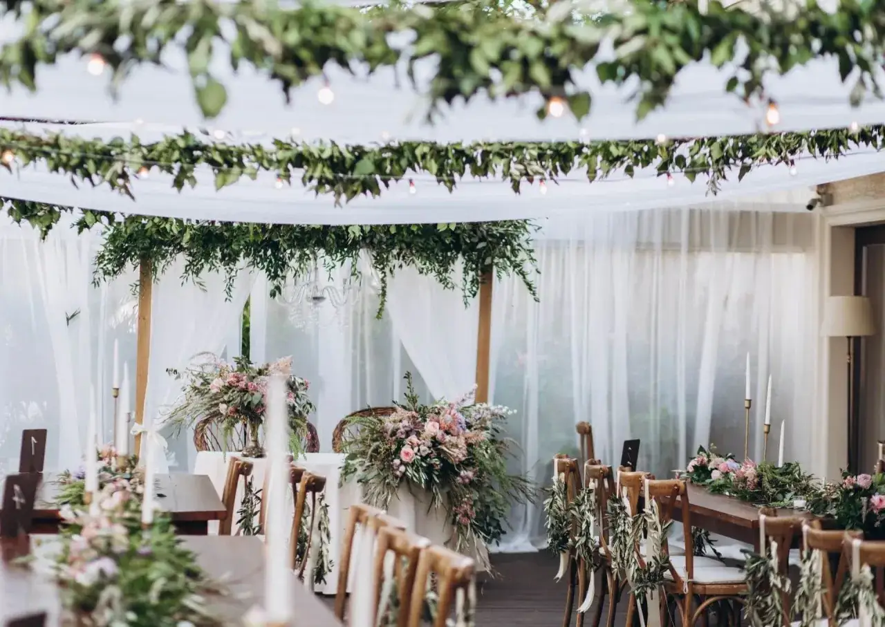 Inspiracja na wesele w stylu boho: zwiewne tkaniny, zielone girlandy, świece i bukiety kwiatów tworzą magiczną atmosferę.