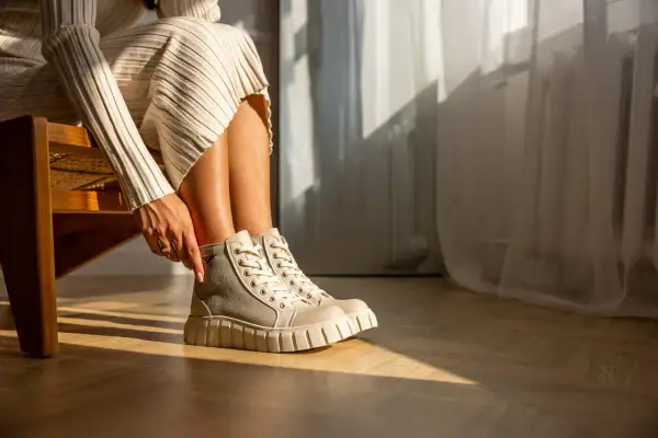 Damskie buty Palladium w beżowo-szarym kolorze na grubej podeszwie, noszone z dzianinową sukienką.