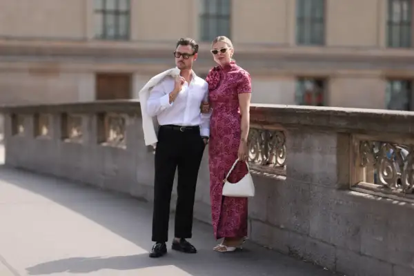 Elegancka para, inspiracja, jak się ubrać do teatru. Mężczyzna w białej koszuli i czarnych spodniach, kobieta w różowej sukni.
