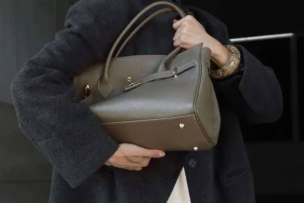 Elegancka, szara torebka na ramię z uchwytami i złotymi elementami. Klasyczne, jakie torebki są teraz modne, to te o prostych, ponadczasowych formach.