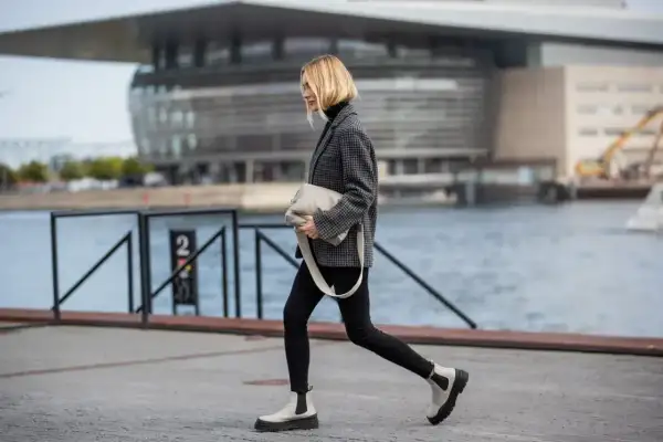 Stylowa kobieta w wąskich spodniach i botkach na grubej podeszwie. Idealne buty do wąskich spodni damskich.