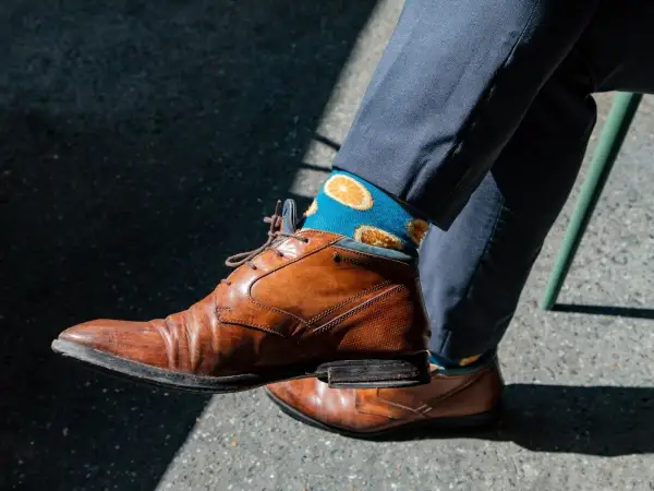 Niebieskie skarpetki w pomarańcze dodają charakteru do eleganckiego garnituru. Idealne pytanie: jakie skarpetki do garnituru?