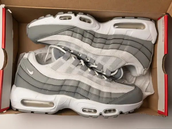 Szare i białe buty sportowe Nike Air Max 95, znane jako ermaksy, leżą w kartonowym pudełku.