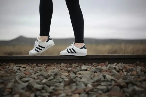 Białe trampki Adidas Superstar z czarnymi paskami i czarne legginsy – idealne buty do legginsów na spacer po torach kolejowych.